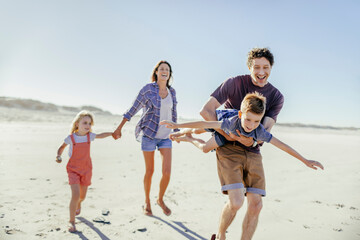 Young caucasian family walking on a sandy beach during their summer vacation