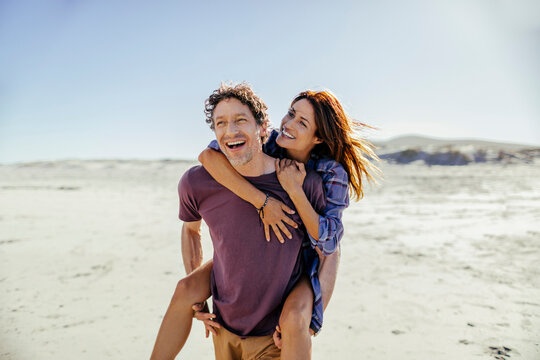 Middle aged caucasian couple walking and having fun on a beach during their vacations