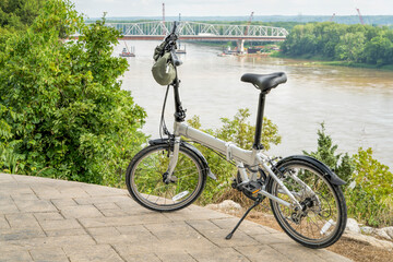 lightweight folding bike on a high shore of the Missouri River above Katy Trail overseeing bridge construction near Rocheport, MO in summer scenery - obrazy, fototapety, plakaty