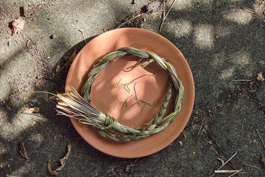 Sweetgrass braid (Hierochloe odorata), also called vanilla grass, on a clay plate outdoors in summer. Overhead view.