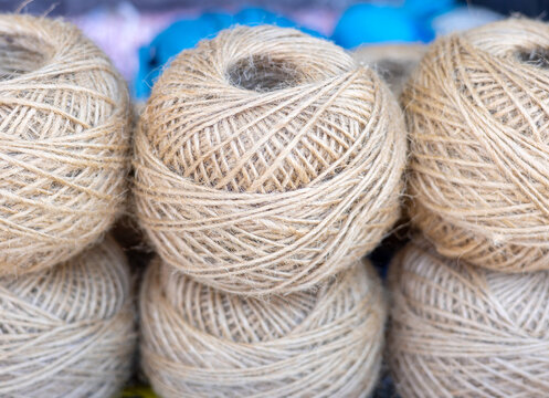 rolls of natural hemp wire for parcel twine, string, packing or diy.fencing strand,polypropylene orange, blue twine.spools in plastic bag,woman hand,market store sale concept