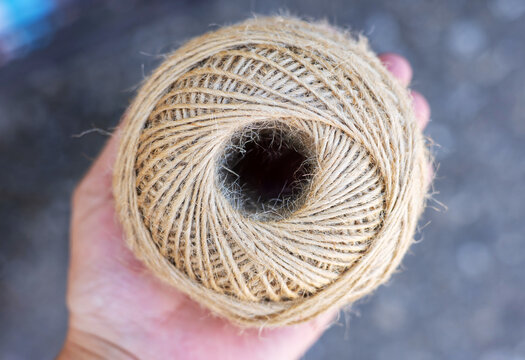rolls of natural hemp wire for parcel twine, string, packing or diy.fencing strand,polypropylene orange, blue twine.spools in plastic bag,woman hand,market store sale concept