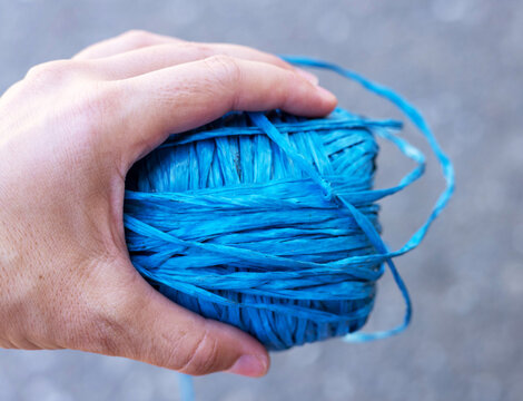 rolls of natural hemp wire for parcel twine, string, packing or diy.fencing strand,polypropylene orange, blue twine.spools in plastic bag,woman hand,market store sale concept