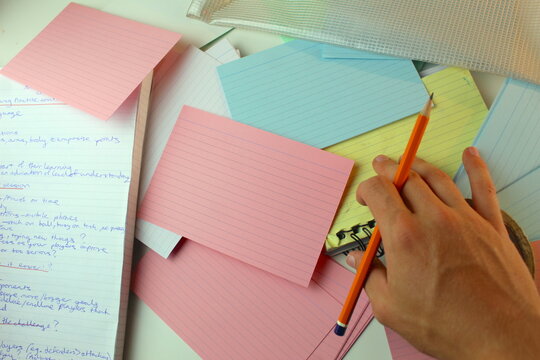 A photo of a student working on a school project at home with their colourful flashcards and notebook. 