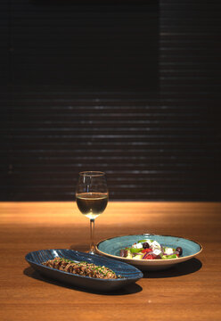 a plate of tuna tataki with a glass of wine and salad