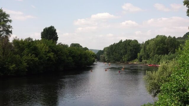 wide river with kayaks among green banks. Perigord, France
