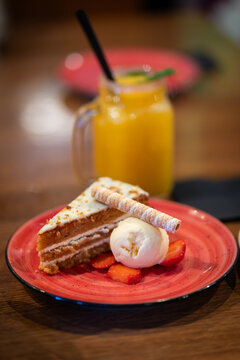 a piece of pie with ice cream and orange juice at the background 