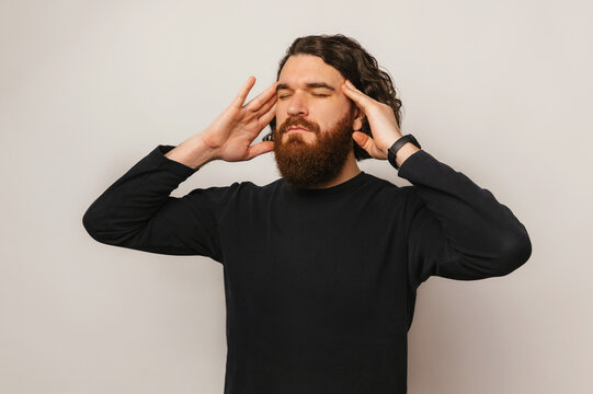 Photo of bearded man standing over white background and thinking about something.