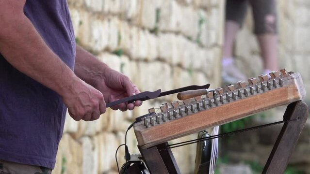 wooden spoons strike the strings of a musical instrument.