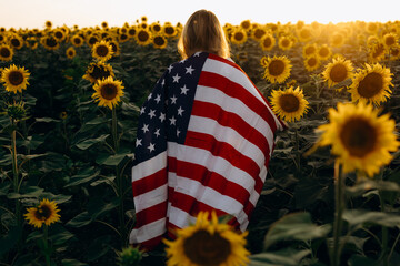 Young woman holding American flag at sunset. America celebrate 4th of July. Independence Day.