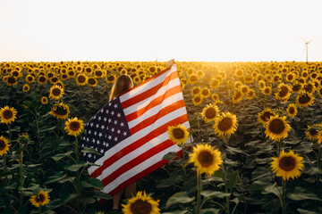 Young woman holding American flag at sunset. America celebrate 4th of July. Independence Day.