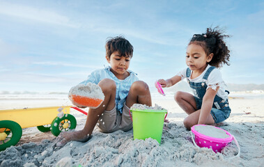 Boy, girl and shovel with bucket, beach sand and digging for playing, outdoor and vacation in summer. Kids, siblings and plastic toys for sandcastle, construction game and together on holiday by sea