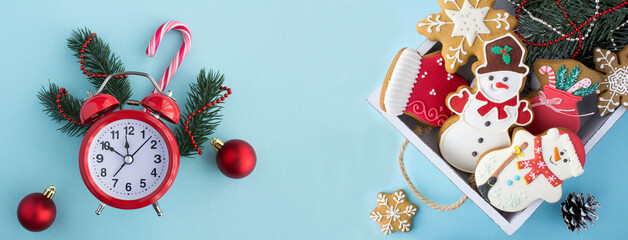 Christmas gingerbread in the white wooden tray and red alarm clock on the blue background. Top...