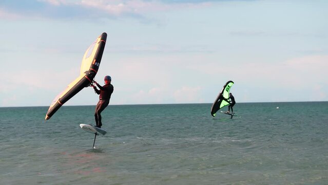 Modern water sport. Hydrofoil ride on the ocean using the wing and the power of the wind. the best place for kitesurfers, video of fit athlete practise hydro foil wing surfing 