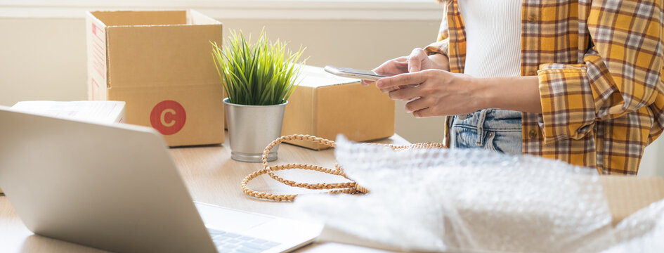 Online seller store, small business entrepreneur asian young woman using smart mobile phone taking photo bag or product with digital camera for promotion advertising sell post on internet market web.