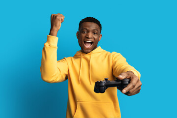 Thrilled black guy gamer with joystick playing video game © Prostock-studio