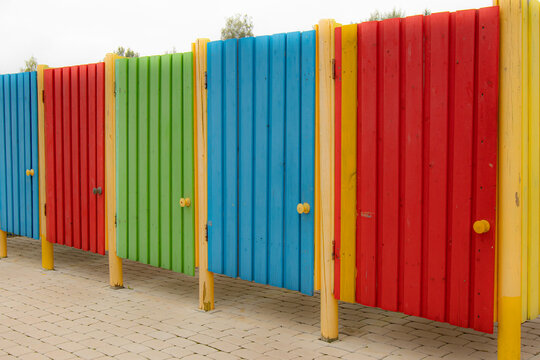 Beach tanning booths in a variety of bright colors. Wooden cabins on the beach