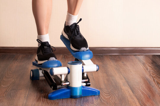Home fitness. Woman doing exercises on stepper at home. close up photo