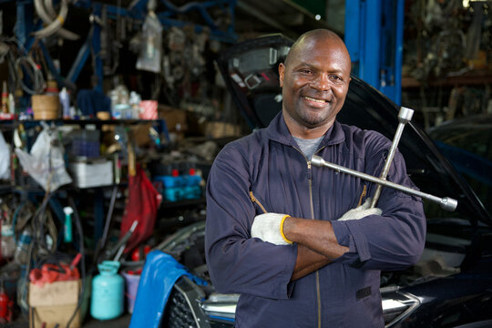 mechanic crossed arms pose and holding lug wrench for fixing a car in automobile repair shop