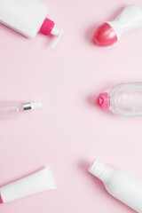 Cosmetic beauty products on pink background. Bottles and tubes with branding mock up. Skin care and beauty concept. Top view, flat lay, copy space