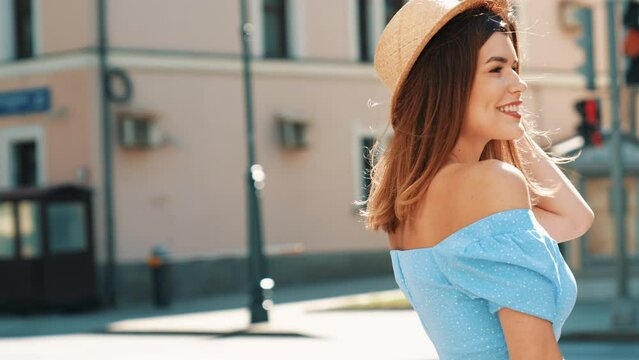Young beautiful smiling hipster woman in trendy summer clothes. Carefree model posing in the street at sunny day. Positive female outdoors. Cheerful and happy. In hat