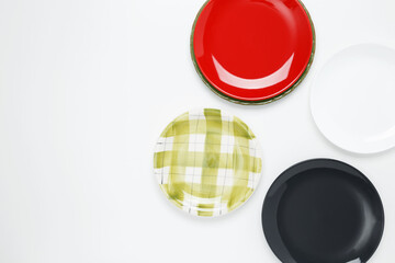 Multicolored dinner plates on a white background. Top view, copy space, flat lay