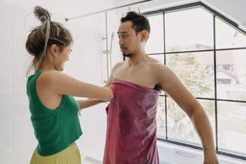 Fototapeta premium Funny and playful asian couple, wife helping husband after taking bath.