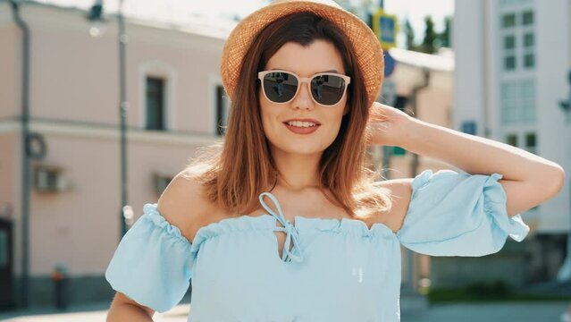 Young beautiful smiling hipster woman in trendy summer clothes. Carefree model posing in the street at sunny day. Positive female outdoors. Cheerful and happy. In hat and sunglasses