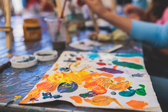 Process of painting, group class of young talented kids students with painting easels, and canvases during lesson of watercolour painting outdoors, drawing class for children in art school