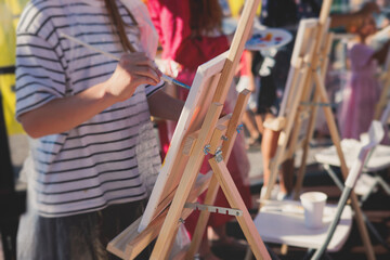 Process of drawing, group class of talented students with painting easels and canvases during...