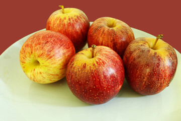 Fototapeta na wymiar Apples on the white plate with burgundy background.