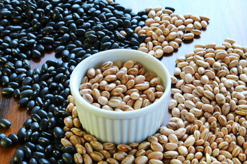 Carioca beans in a bowl. Brazilian grains scattered on the wooden table.