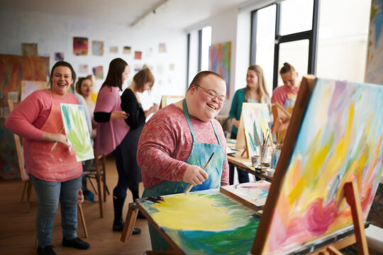 Young smiling man with Down syndrome on art workshop with a group of students, learning a new skill. Social integration concept. - Powered by Adobe