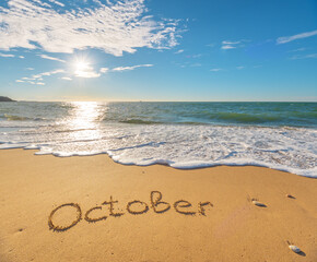 Fototapeta na wymiar October word on sea sand