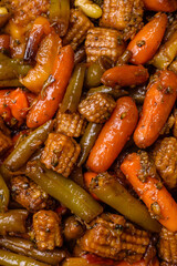 Mix of vegetables corn, carrots, peppers, broccoli, onions in teriyaki sauce on a ceramic plate