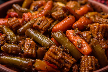 Mix of vegetables corn, carrots, peppers, broccoli, onions in teriyaki sauce on a ceramic plate