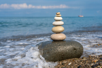 Pyramid of stones for meditation lying on sea coast at sunset - 638059505