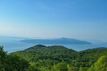 A panoramic view on the Mediterranean Sea in Croatia from Vojak. The mountain is overgrown with lush green plants. Few islands in the back. Early morning hiking by the sea. Clear, blue sky. Remedy