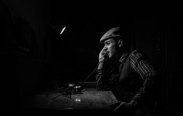 Vintage Black and White Portrait of a Man in the 1940s Speaking on the phone. Retro portrait from the 20th century. Man dressed peaky blinders style. Portraits from the 20th century.