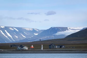 Foto op Plexiglas Buildings and little lighthouses on coast around Longyearbyen, Spitsbergen, Svalbard, Norway. Mountains with glaciers and snow in background. © Iwona