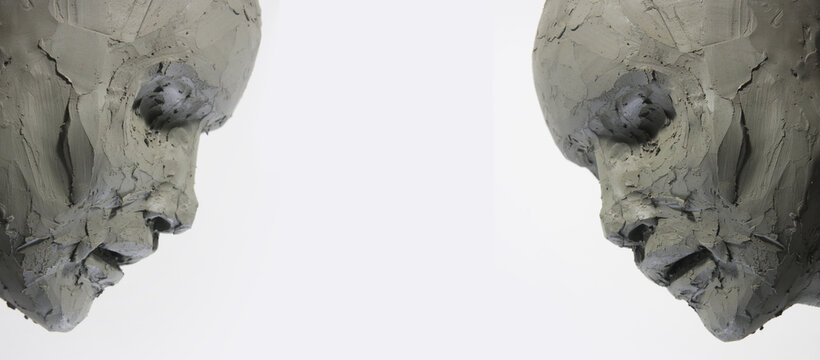 Pair of clay faces on a white background. Portrait, sketch without eyes. Artwork in process of creation. Artistic banner for modelling and sculpture, fine arts workshop, contemporary art.