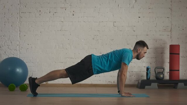 Closeup shot. Man fitness coach in sportswear doing classic push ups exercise for online class at the home studio.