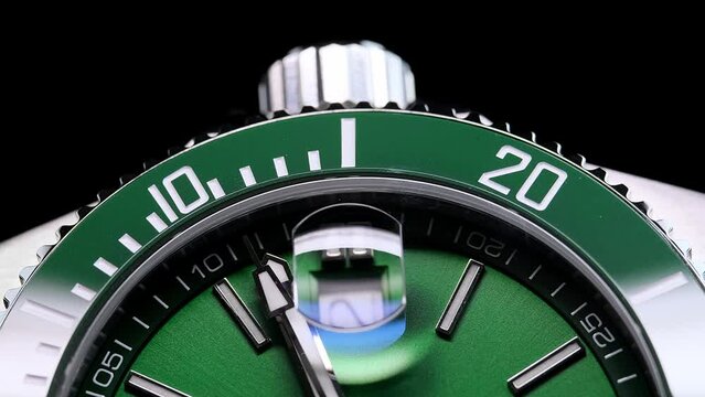 Stylish Luxury Man Wrist Watch With Moving Hand And Multiple Dials. Men's watch in metal with sapphire crystal. Closeup view of rotating watch, running second arrow. green dial. Cyclops watch