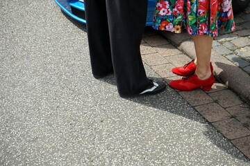 Frau im bunten Sommerkleid mit Blumenmuster und roten Schuhen mit Tanzpartner im Stil der...