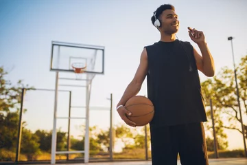 Küchenrückwand glas motiv black man doing sports, playing basketball on sunrise, active lifestyle, sunny summer morning © mary_markevich