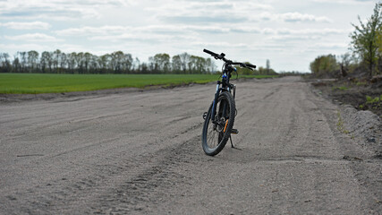 Obraz premium Mountain bike. stands on a field road. spring or autumn. concept of cycling, repair or breakage, sports, outdoor activities. bike on trail, front wheel in focus. healthy lifestyle