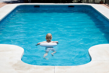 Little boy with inflatable swim ring in the swimming pool
