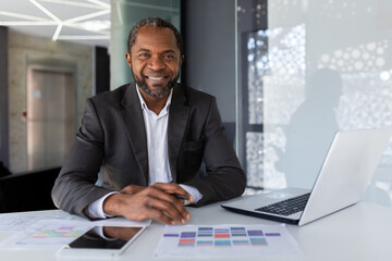 Portrait of mature successful adult African American businessman, boss smiling and looking at...