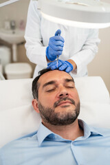 Handsome middle age man receiving advanced Platelet Rich Plasma PRP treatment against hair loss....