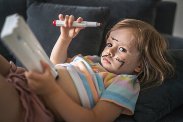 caucasian girl toddler with painted color draws and stains on face